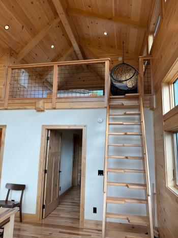 Interior cabin with loft and a custom wood ladder leading up to it. Wood ship lap interior walls.