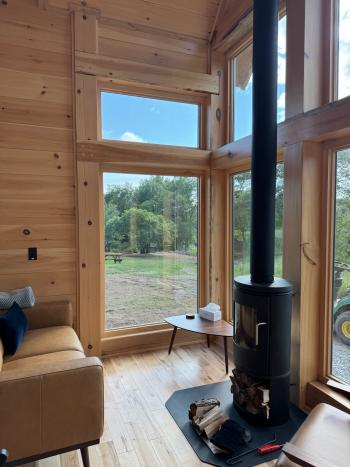 Living room with wood burning stove and large windows opening onto the scenic views.
