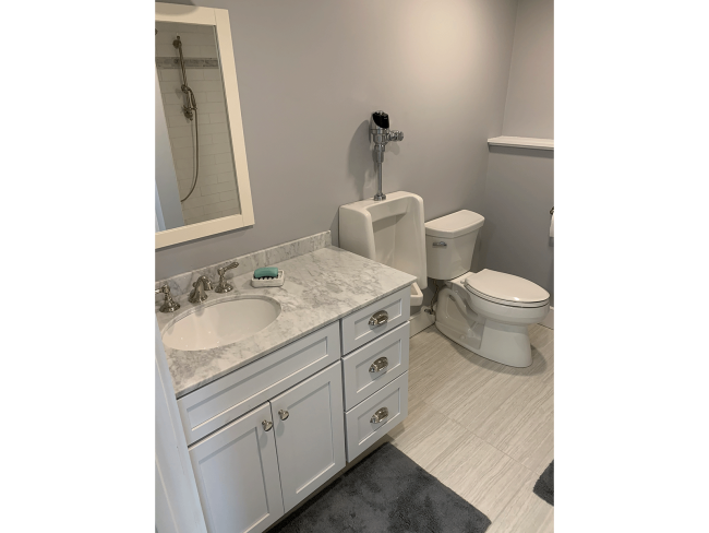 Basement bathroom with new vanity, urinal and toilet.