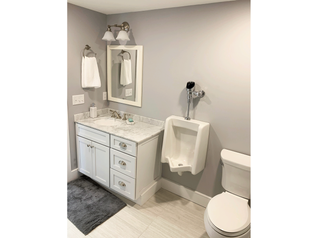 An alternative view of the bathroom vanity, urinal, and toilet.