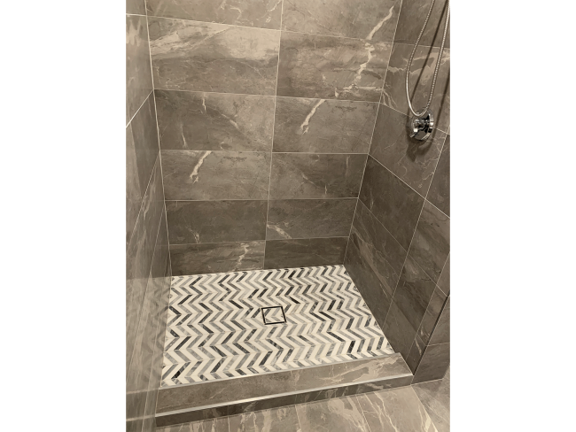 Walk in marble shower with white and gray tile floor.