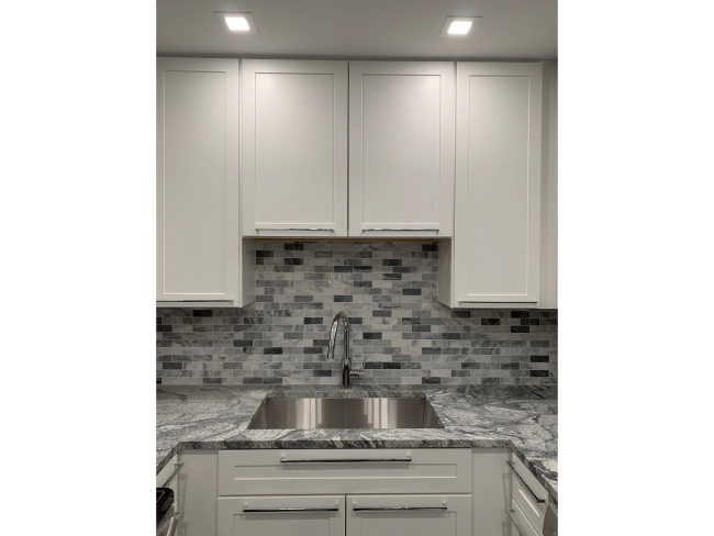 Kitchen remodeled with gray backsplash, new cabinets, and cabinetry.