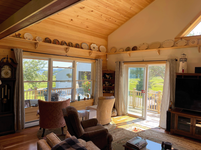 Living room with wood slat ceiling and trim overlooking the patio and yard/