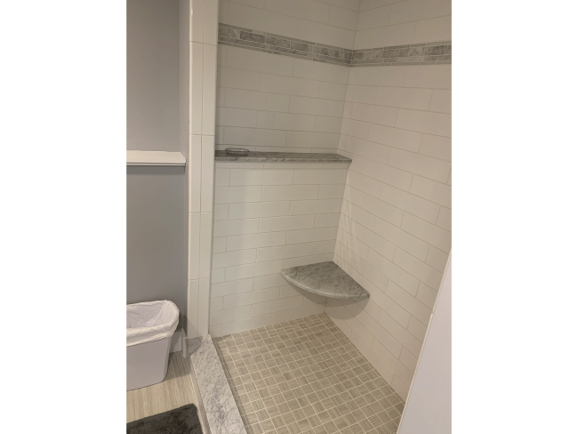 Walk in shower with white tile and built in shelving.