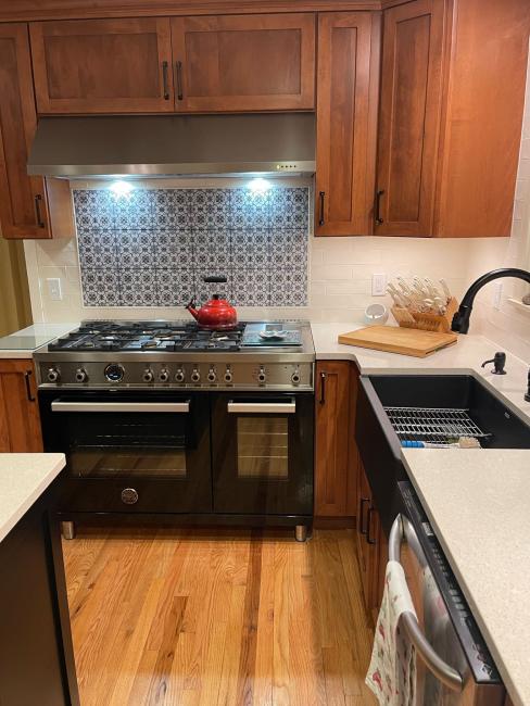 New black stove and black apron sink with backsplash and lighting.